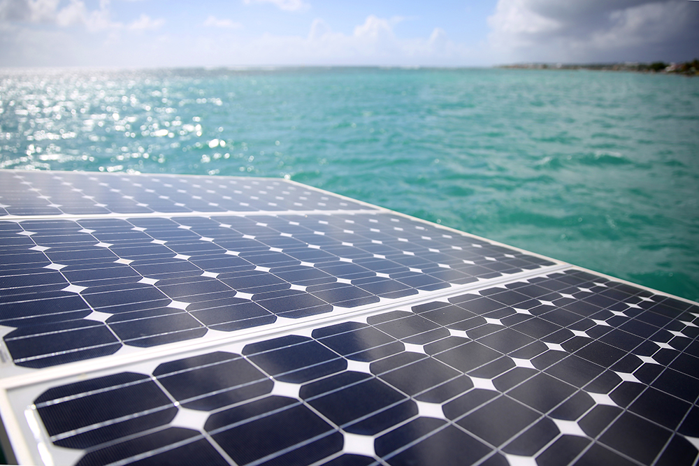 Nahaufnahme von Solar Paneelen mit Blick auf von der Sonne glitzerndes Meer symbolisiert die Nutzung von Solarenergie auf den Philippinen mit Net-Metering